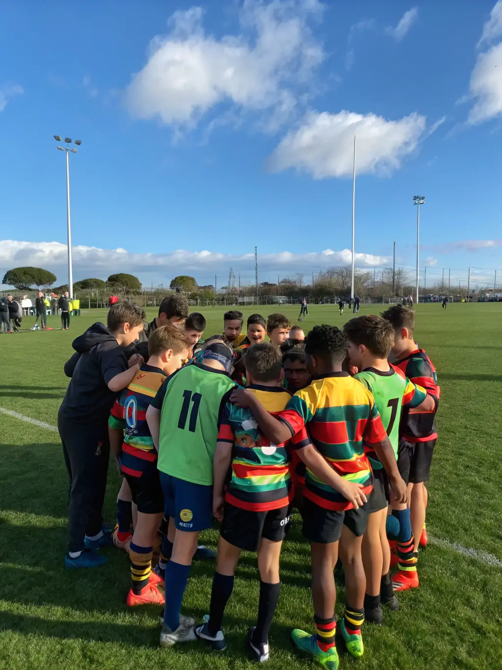A diverse group of children participating in a rugby clinic, demonstrating inclusivity and accessibility in sports, with coaches providing guidance and encouragement.